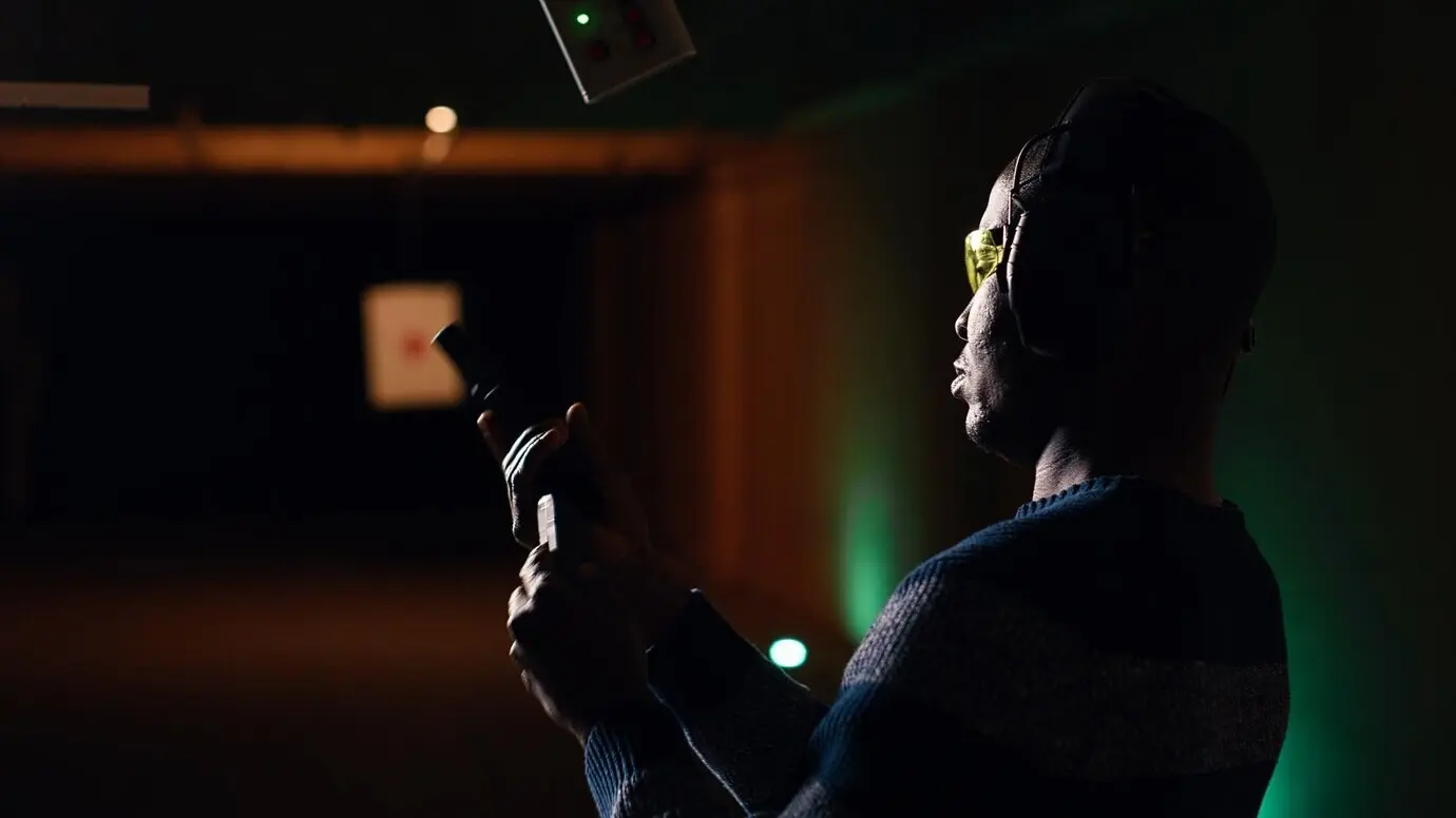 Клиент тира смотрит в увеличительный прибор, чтобы проверить, попал ли он в яблочко.